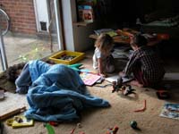 A quieter image. M is tired and sleeps amidst the debris of our living room; D and E are playing quietly. And I'm watching
